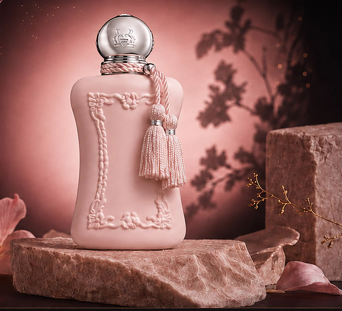 Flacon du parfum Delina de Parfums de Marly, posé sur un socle de pierre, entouré de pétales roses et d’un voile bordeaux.